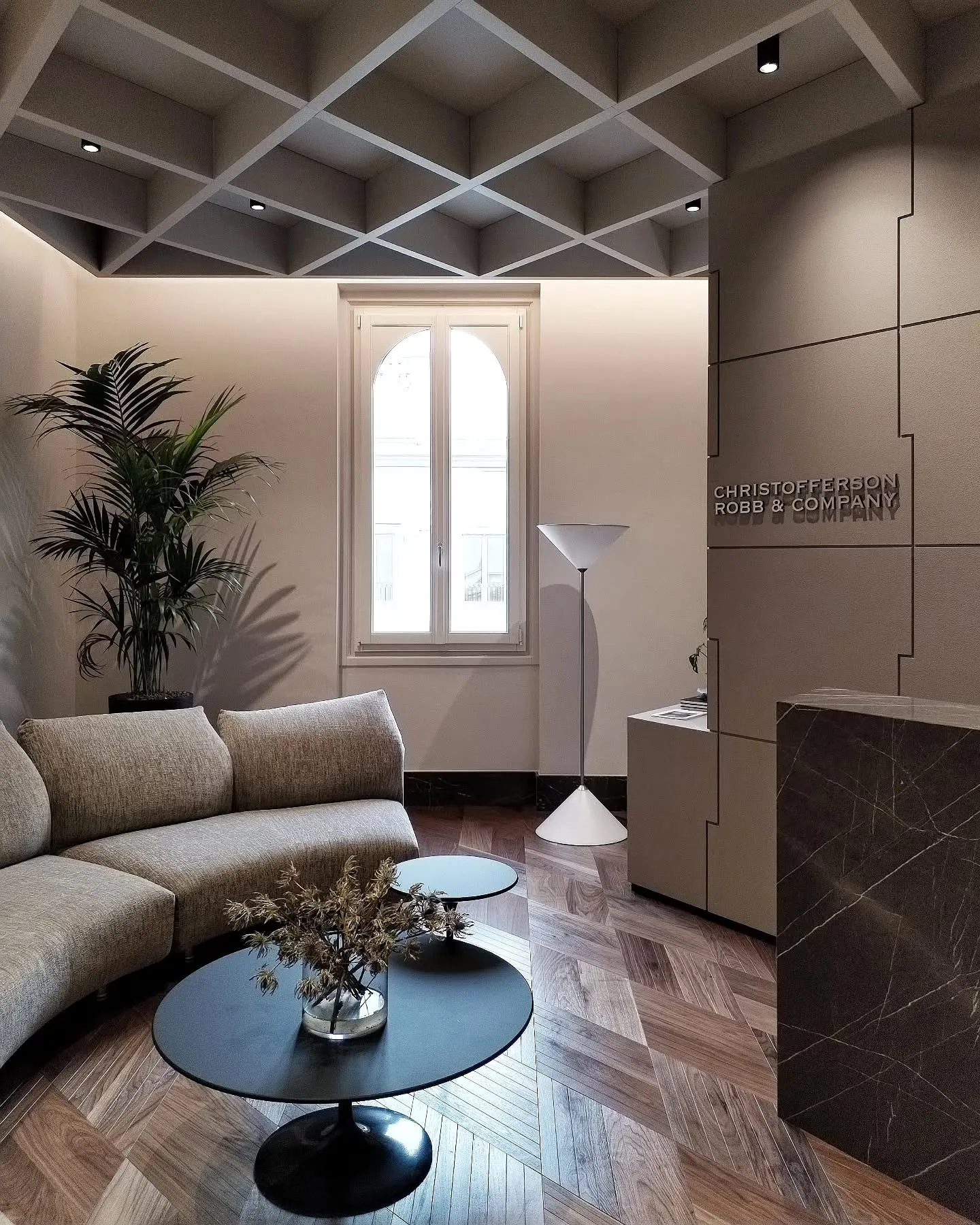 Christofferson, Robb & Company office lounge in Milan with a coffered ceiling, pale sofa and round table
